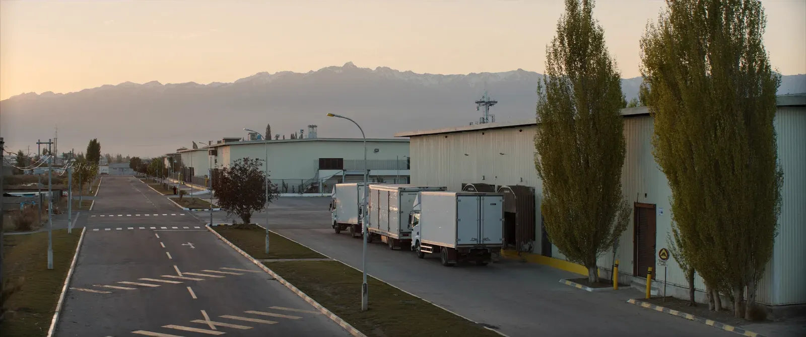 Trucks loading at the warehouses of an industrial park, with the mountain range behind
